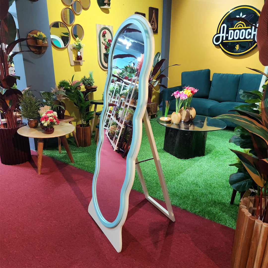 Side view of the Adooch wavy freestanding mirror showing its sturdy stand, placed in a colorful showroom